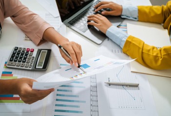 Manos de empresarios analizando informes financieros con gráficos y calculadora
